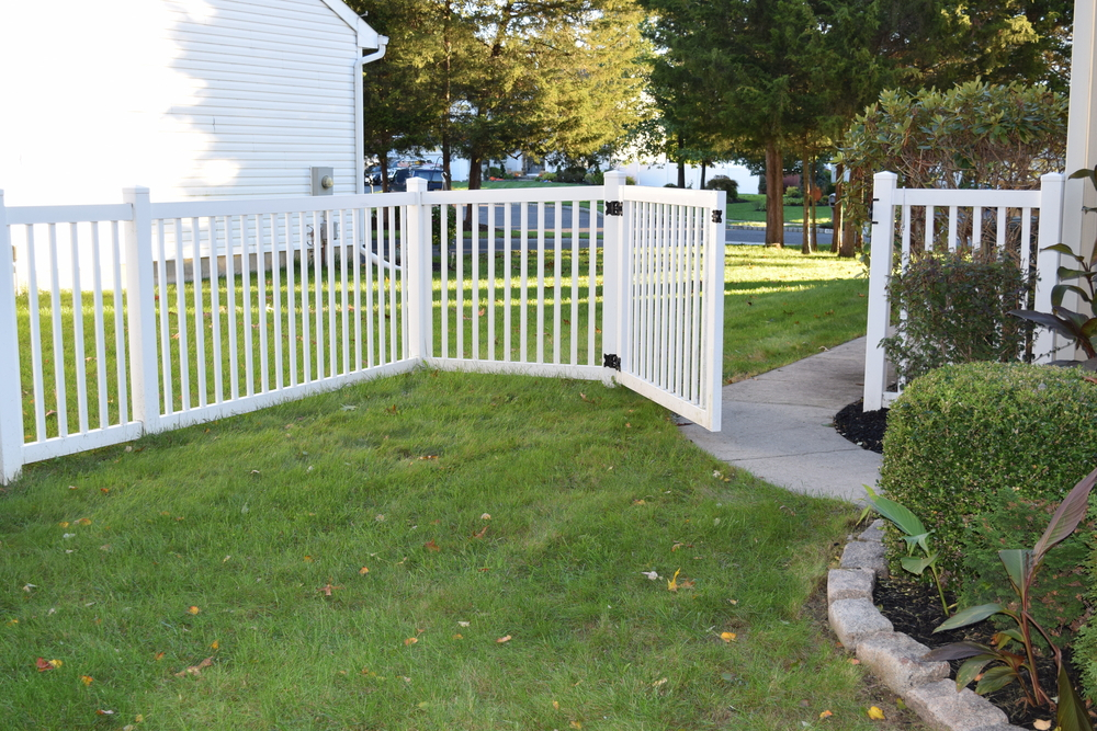 a white fence and grass in front of a house